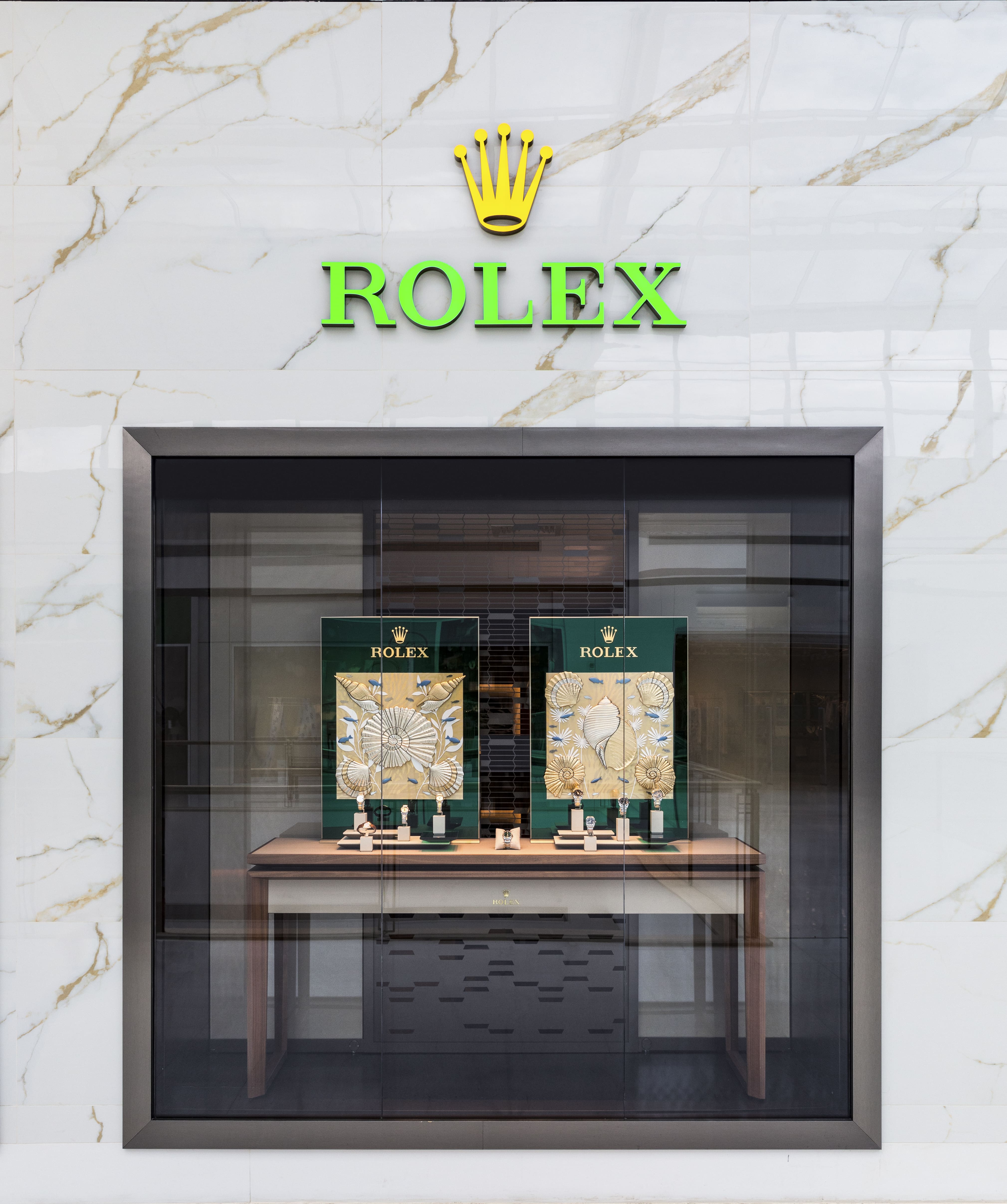 Vários relógios Rolex expostos em vitrines elegantes com quadros ao fundo