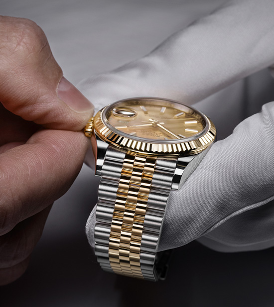 Mão masculina ajustando a hora no relógio Rolex utilizando uma luva branca