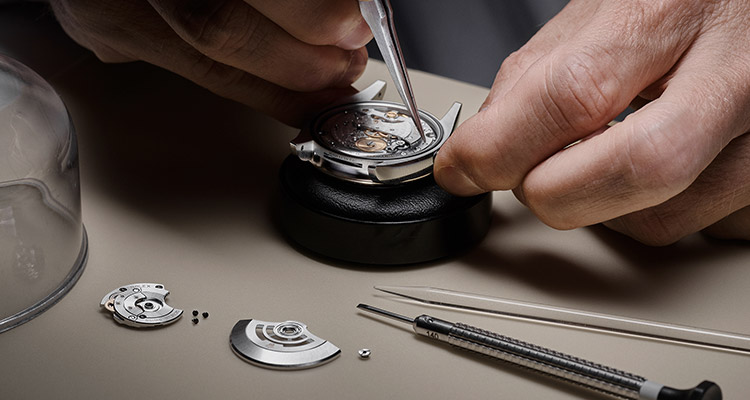 Mãos de homem fazendo manutenção no relógio Rolex usando pinça especial